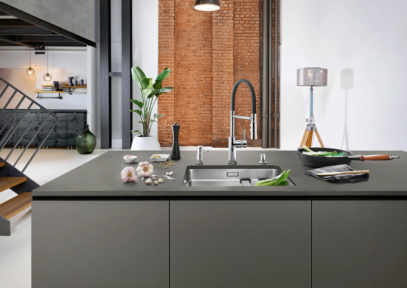 Tuğla duvarlı loft mutfakta koyu adada çelik evye ve spiralli armatür